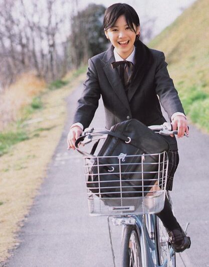 制服を着て自転車に乗っている女優の夏帆