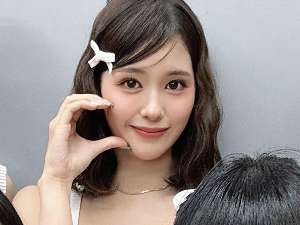 石井蘭(RAN)ボブヘアでリボンの髪飾りをつけてハートポーズをしている